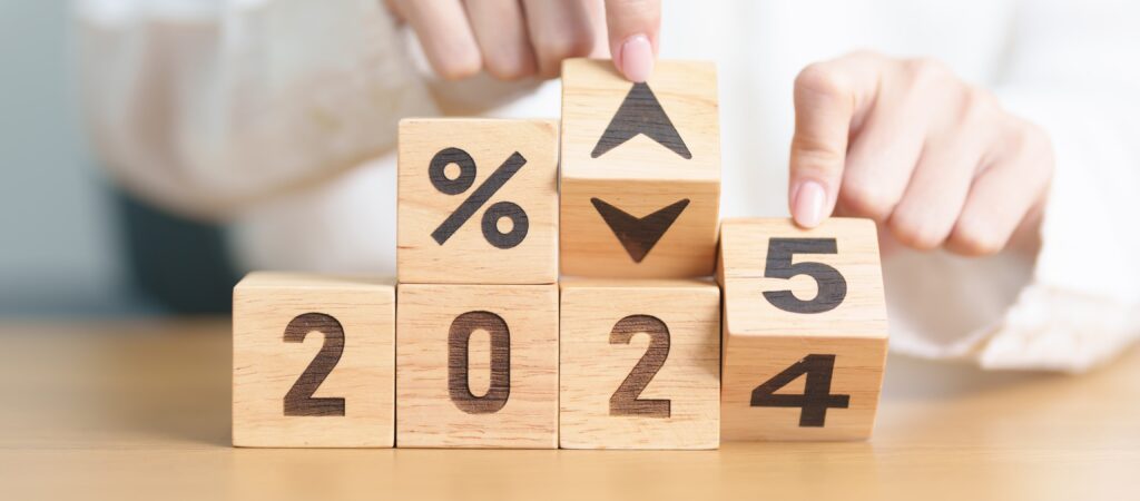 Wooden blocks displaying "2024" with percentage and up/down arrows, being changed to "2025" to represent shifting interest or mortgage rates.